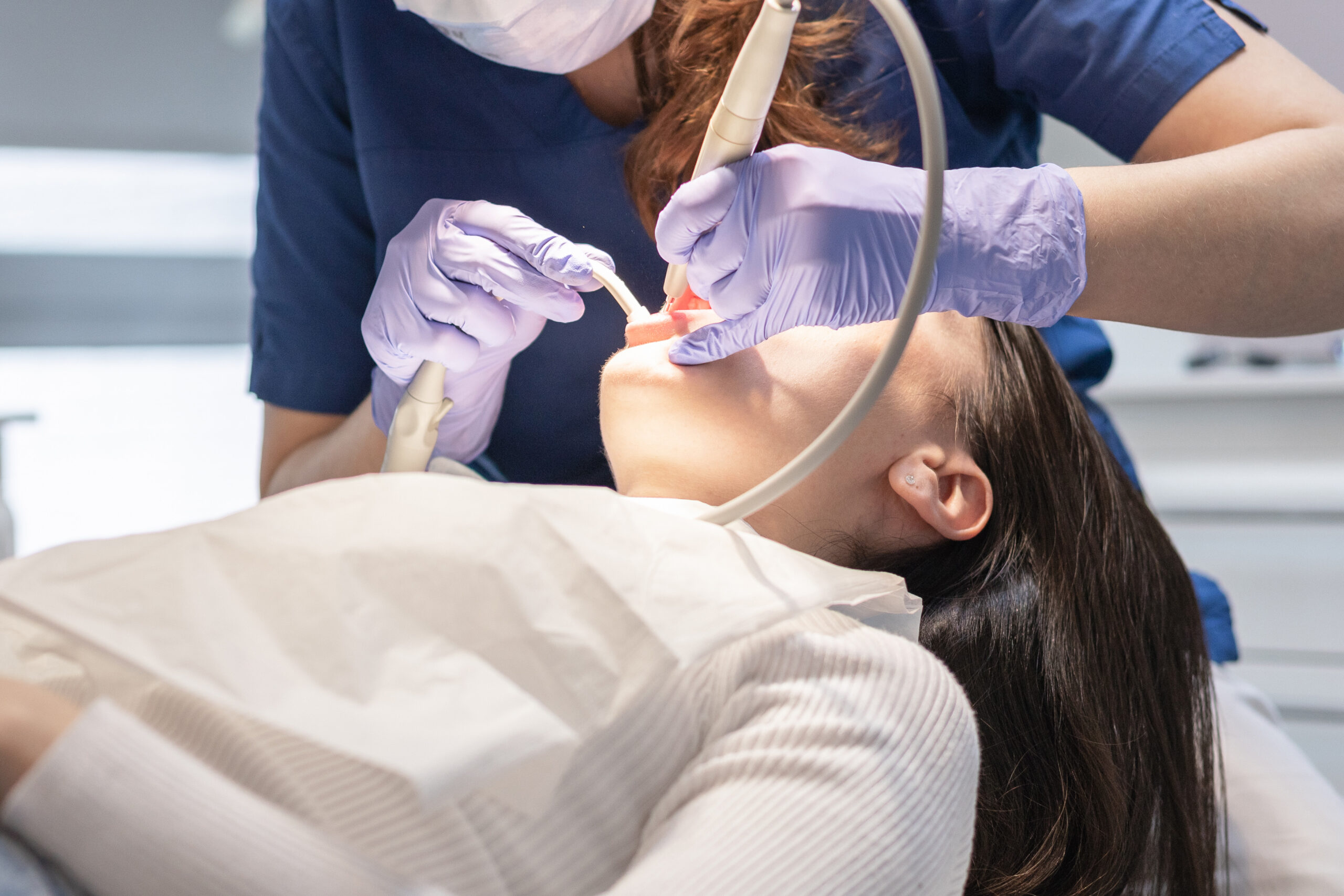 Dental hygienist performing professional teeth cleaning on a patient in a dental clinic.
